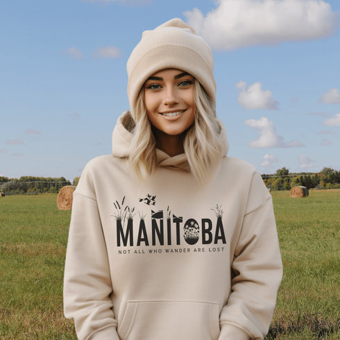 Featuring a serene prairie landscape, the design captures the essence of the heartland with wildflowers and prairie grasses growing out of the letters Manitoba.